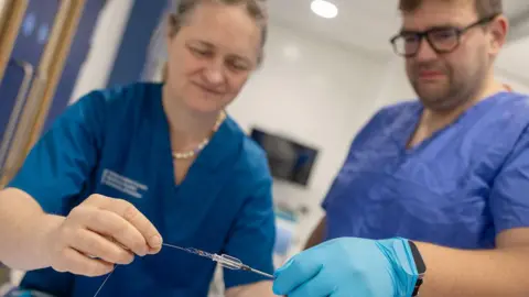 University of Dundee Professor Grunwald and another medic hold a wire as part of the thrombectomy