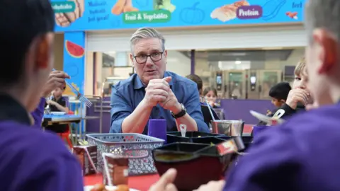 PA Media Prime Minister Sir Keir Starmer helps serve lunch during a visit to Welland Academy, Peterborough, to talk about the importance of free school meals and tackling the cost of living.