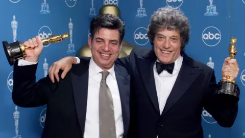Getty Images Screenwriters Marc Norman (L) and Tom Stoppard hold their Oscar statues backstage at the 71st annual Academy Awards in Los Angeles, 21 March, 1999.