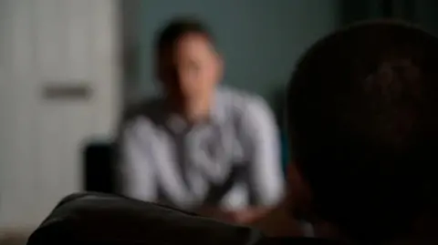 An image of a man doing an interview but the camera is deliberately out of focus. 