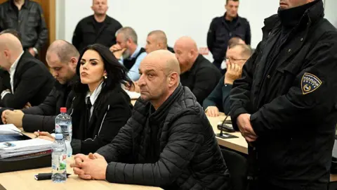 AFP Dejan Jovanov-Deko (C), one of the defendants and owner of the nightclub, looks on at the start of the trial for the blaze that killed 63 in Kocani earlier in 2025, in the courtroom next to the Idrizovo correctional facility near Skopje on November 19, 2025