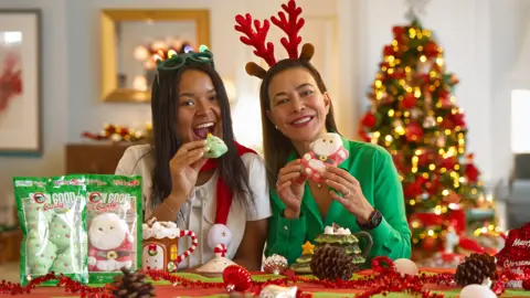 Sow Good In a Christmas themed setting Claudia Goldfarb holds a large sweet and wears reindeer antlers on her head. 