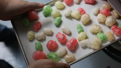 Getty Images A tray of freeze dried sweets being pulled out of an oven. The look like a puffed-up version of gummy bears.