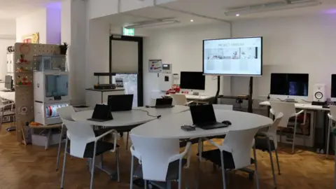Makerspace Penarth / Vale of Glamorgan Council A group of tables with computers laid out at each seat. There is also a projector in the background.