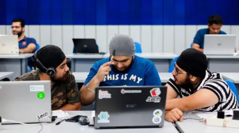 AFP via Getty Images Indian undergraduate students work on their computers as they take part in HackCBS, a 24 hour event of software development. Students gathered in teams to take part in a challenge to develop their ideas in the fields of Internet of Things (IoT), Artificial Intelligence (AI) an Blockchain among others. 