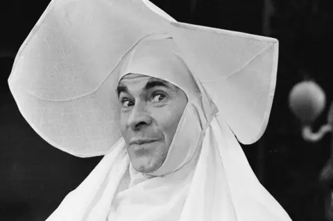Getty Images Stanley Baxter dressed as a nun smiling at camera. He has a huge wimple on.