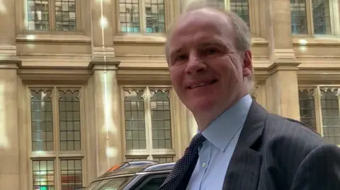 Daniel Cloake A man in a suit walks through London