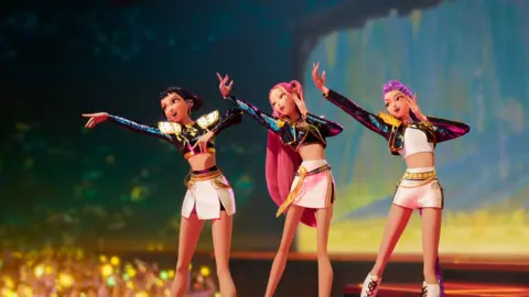 Netflix Scene from KPop Demon Hunters with three female animated characters performing on stage