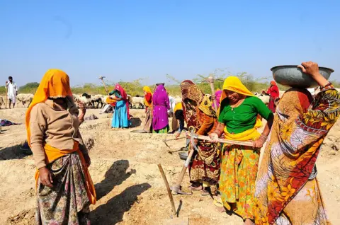 Mint via Getty Images Women in bright clothes, with heads covered doing manual labour under MNREGA (Mahatma Gandhi National Rural Employment Gurantee Act) in Jaipur, India. 