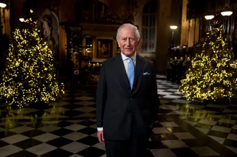 PA Media King Charles in front of Christmas trees in Westminster Abbey which were used for the Princess of Wales's carol concert