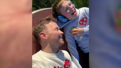 James Hunt James lies on the floor smiling next to Tommy who is also smiling and wearing headphones