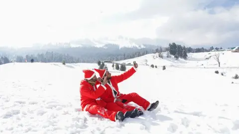 Getty Images Two men dressed as Santas take a selfie in the snow in Gulmarg in Indian-administered Kashmir