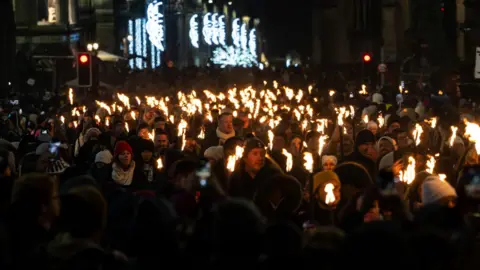 Ian Georgeson A group of people carrying flaming torches during the torchlight procession in Edinburgh