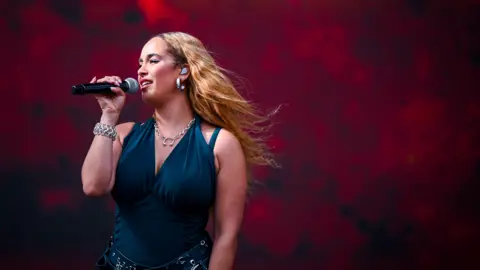 Jorja Smith on stage with a microphone in a blue outfit