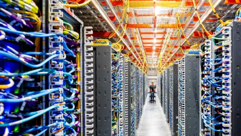 Reuters A technician pushing a cart walks through rows of wires inside a data centre.