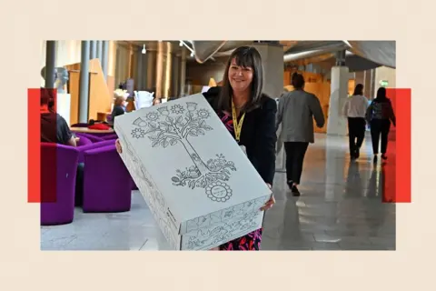 Ken Jack/Getty Images Clare Haughey holds a box