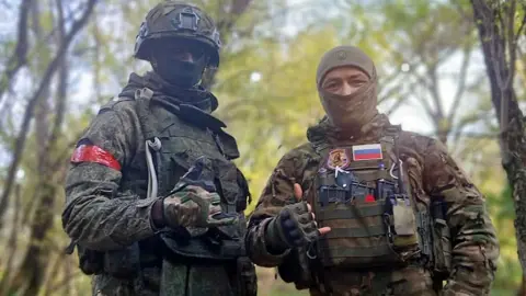 Kuloba family David Kuloba and a Russian soldier in full combat gear pose for the camera in a forest