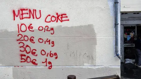 AFP via Getty Images This photograph shows graffiti indicating drug prices on the walls of The Bel Horizon tower, located in the 3rd arrondissement of Marseille, on December 3, 2025