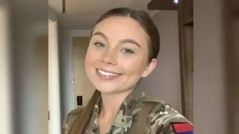 Family Handout Jaysley Beck smiles at the camera in her camouflage army uniform. She has her brown hair tied back in a ponytail