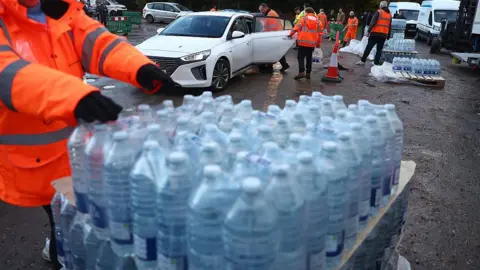 Getty Images Volunteers from South-East Water assist members of the public load bottled water into their vehicles at a distribution point