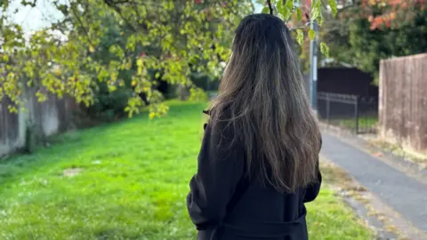 BBC Image of a woman standing by a tree outside.