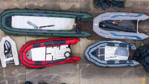 Dan Kitwood/Getty Images Small boats and outboard motors used by migrants to cross the Channel are seen from above, stored at a Home Office facility, in a photo taken last month