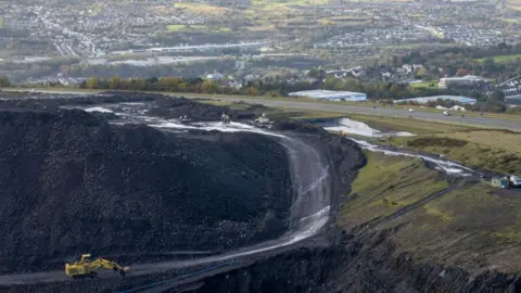 Matthew Horwood/Getty Images The edge of the main mining void at Ffos y Fran opencast coalmine.  Beyond which the A4060 + homes and businesses in Merthyr Tydfil are visible.