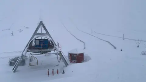 Lecht Ski Centre A snow covered mountain with ski runs marked out and a triangular shaped structed covered in in snow