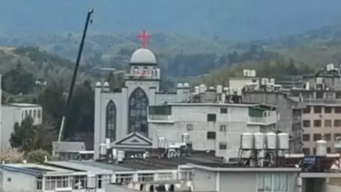 ChinaAid A crane pictured above the red cross of a church in a Chinese city. The church is the tallest among all the other buildings seen in this photograph
