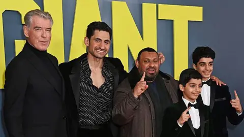 Getty Images Group picture of (left to right) Pierce Brosnan, Amir El-Masry, Prince Naseem, Ghaith Saleh and Ali Saleh posing together at a screening in front of the Giant title on a backdrop.