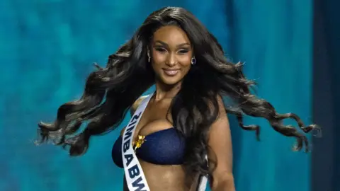 Getty Images Miss Universe Zimbabwe, Lyshanda Moyas, swishes her long hair during a swimwear round at a beauty pageant on 21 November 2025 in Bangkok, Thailand. 