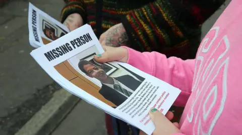 Pacemaker The picture shows a woman wearing a pink top holding a missing person poster with Noah Donahoe's, picture on it  