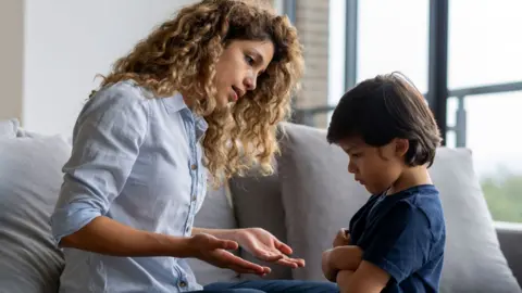 Getty Images Young boy, with his arms crossed and head down, refuses to negotiate with his mother