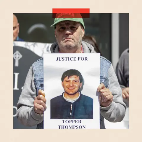 PA Media Eugene Thompson holds up a poster featuring a photo of his brother 