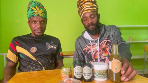 Gemma Handy High Priest Selah of Antigua’s Nyabinghi community, left, and fellow Rastafarian Andre Solomon, with some of the the community's cannabis products


