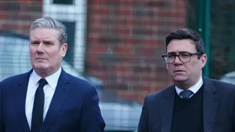 PA Media Starmer and Burnham walk alongside one another both in suits looking glum