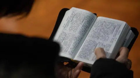 Getty Images A worshipper in church holding open a Mandarin bible
