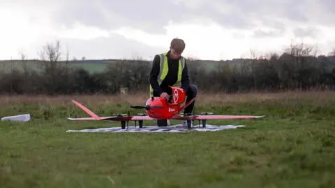 BBC A man wearing a hi vis vest assembles a drone at an airfield in Oxfordshire
