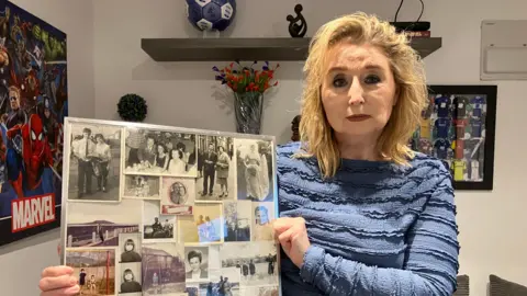 BBC Sue Paige, a woman in a blue long-sleeved too is holding a collage of black and white photos of her parents