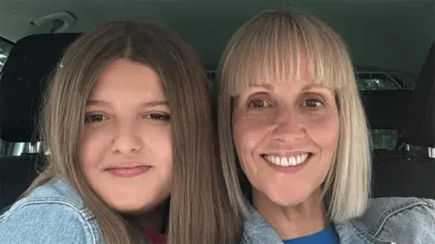 Humberside Police Grace Keeling and Sarah Keeling looking at the camera while sat in a car. Grace has long brown hair and Sarah has long blond hair, both are wearing blue denim jackets
