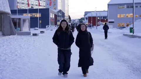 Young women walk on a snowy street in Nuuk, Greenland