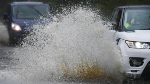 Getty Images Vehicles travel through areas of flooding.