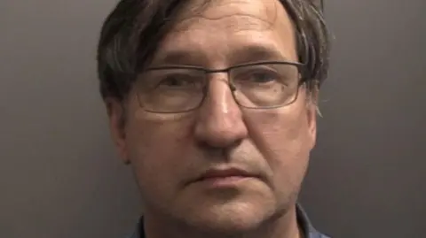 Humberside Police / Reuters Police custody picture of Vladimir Motin. He has short dark hair with a parting and is wearing glasses. He is staring into the camera against a grey wall.