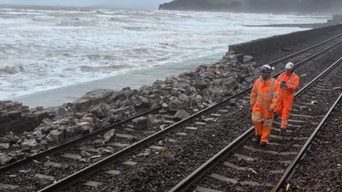 BBC/Johnny Rutherford Railway workers are seen inspecting a crumbled sea wall at Dawlish.