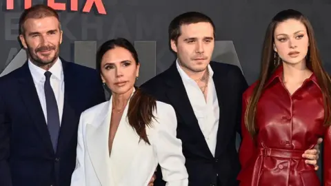 Getty Images David and Victoria Beckham pose with Brooklyn Beckham and Nicola Peltz at the premiere of David’s self-titled 2023 Netflix documentary
